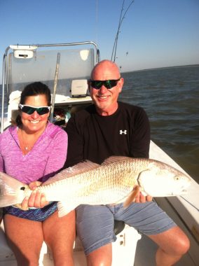 A couple holding a redfish on a fishing charter